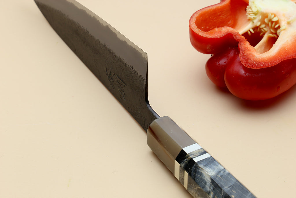Gyuto chef’s knife close-up, dark blue blade and beige handle with striped bolster.
