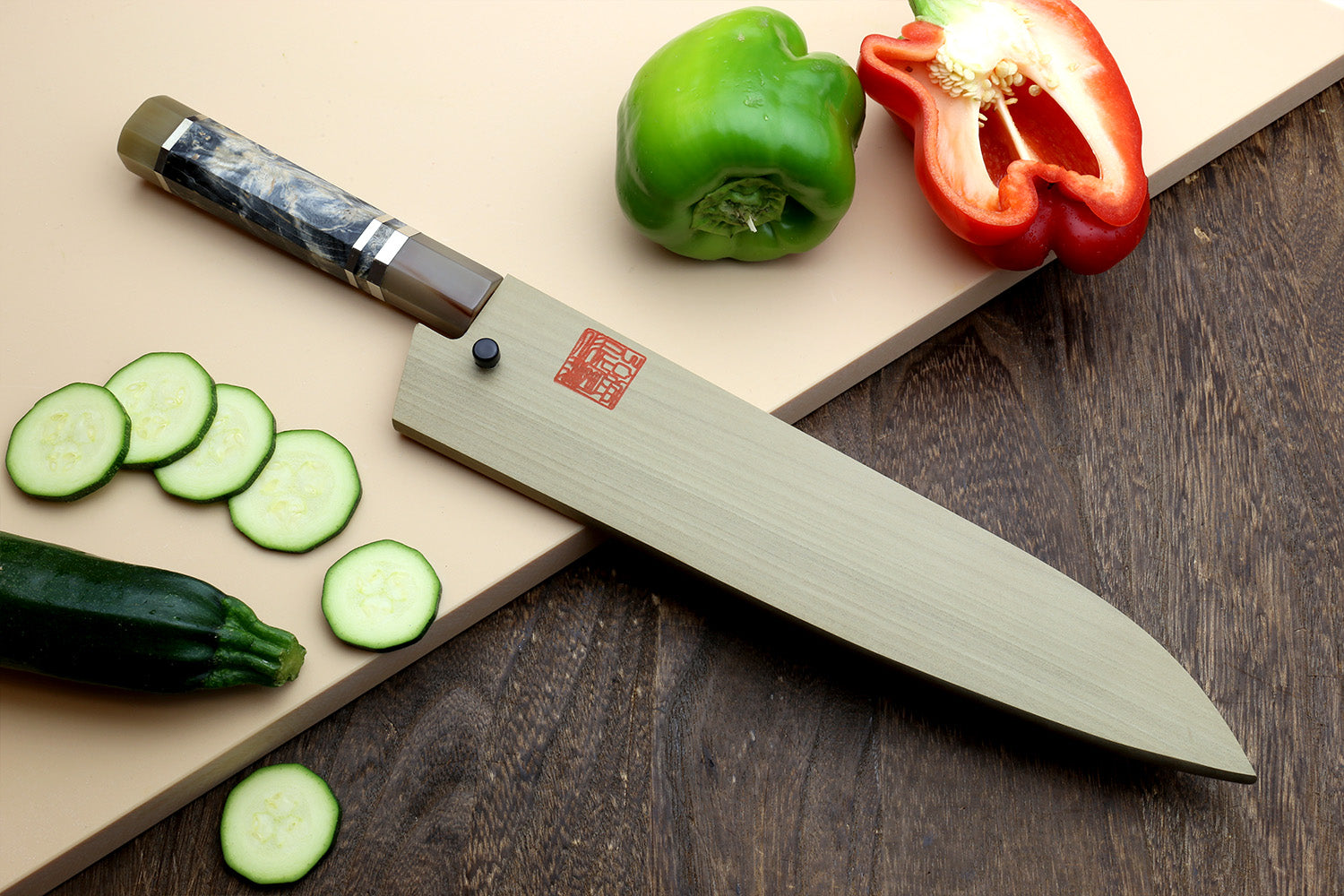 Gyuto chef’s knife with beige handle, dark blue mottled blade and striped bolster.
