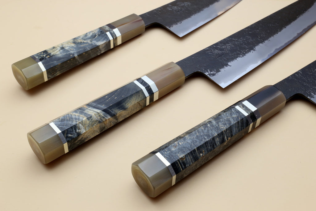 Gyuto chef’s knife, mottled blue steel blade with beige handle and striped bolster.
