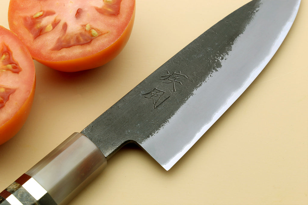 Paring knife close-up of silver blade with stamped mark and dark handle.