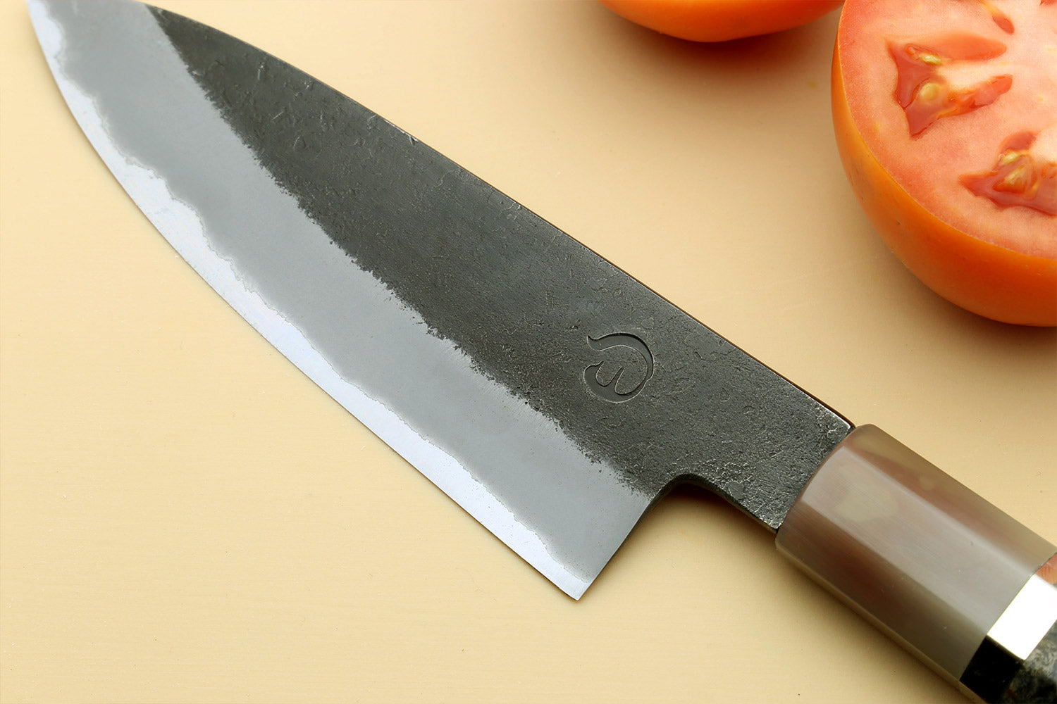Paring knife close-up of silver blade with stamped logo and dark handle.