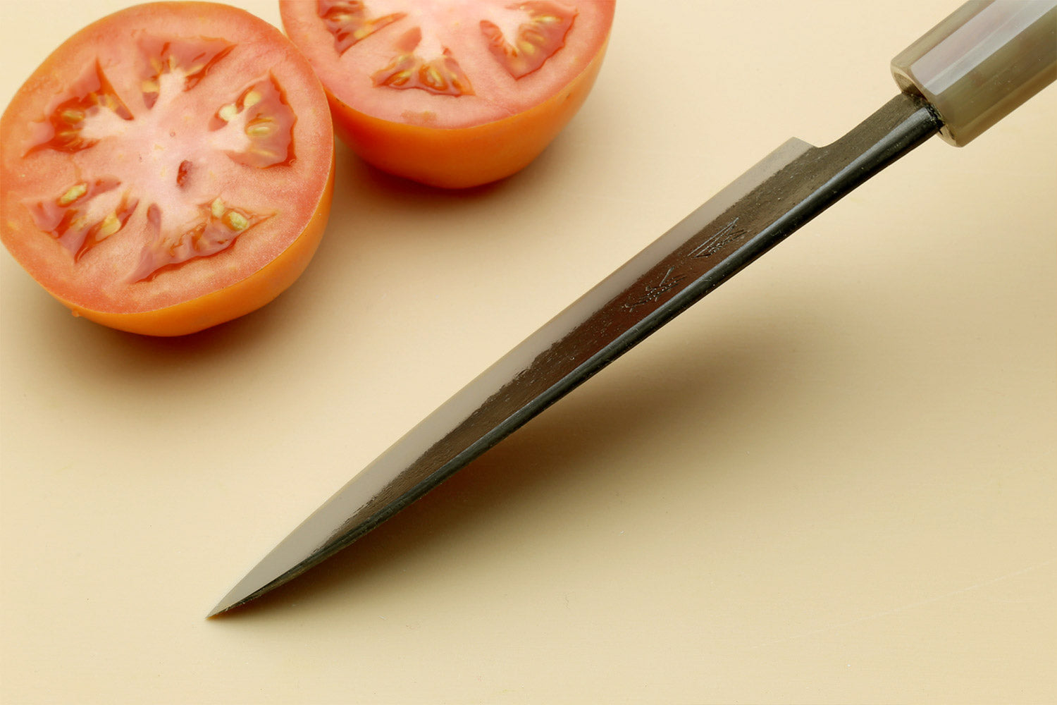 Paring knife angled view with silver blade and dark wood handle.