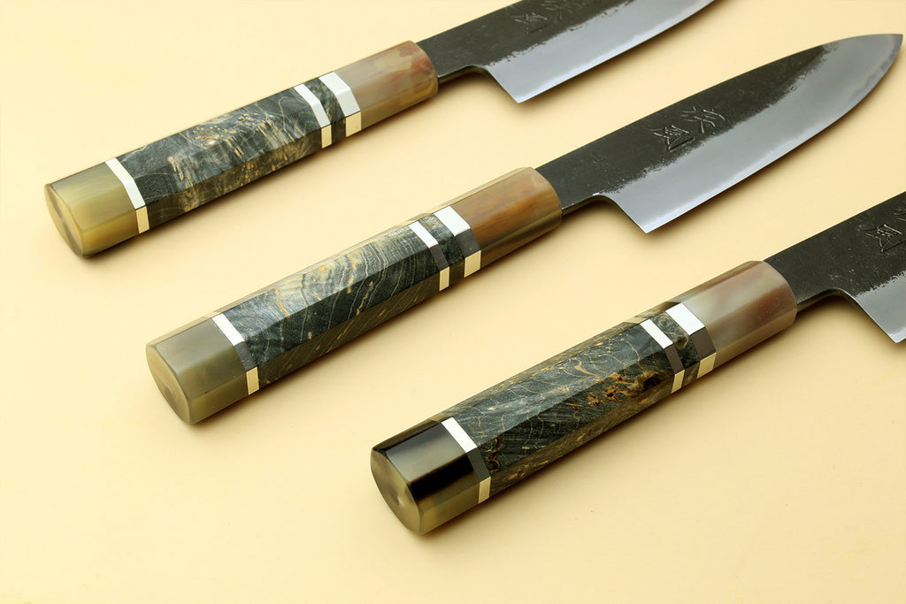 Set of paring knives with dark handles and silver blades, one showing stamped logo.