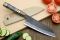 Santoku knife with blue-steel blade and dark handle, with tomato and cucumber slices