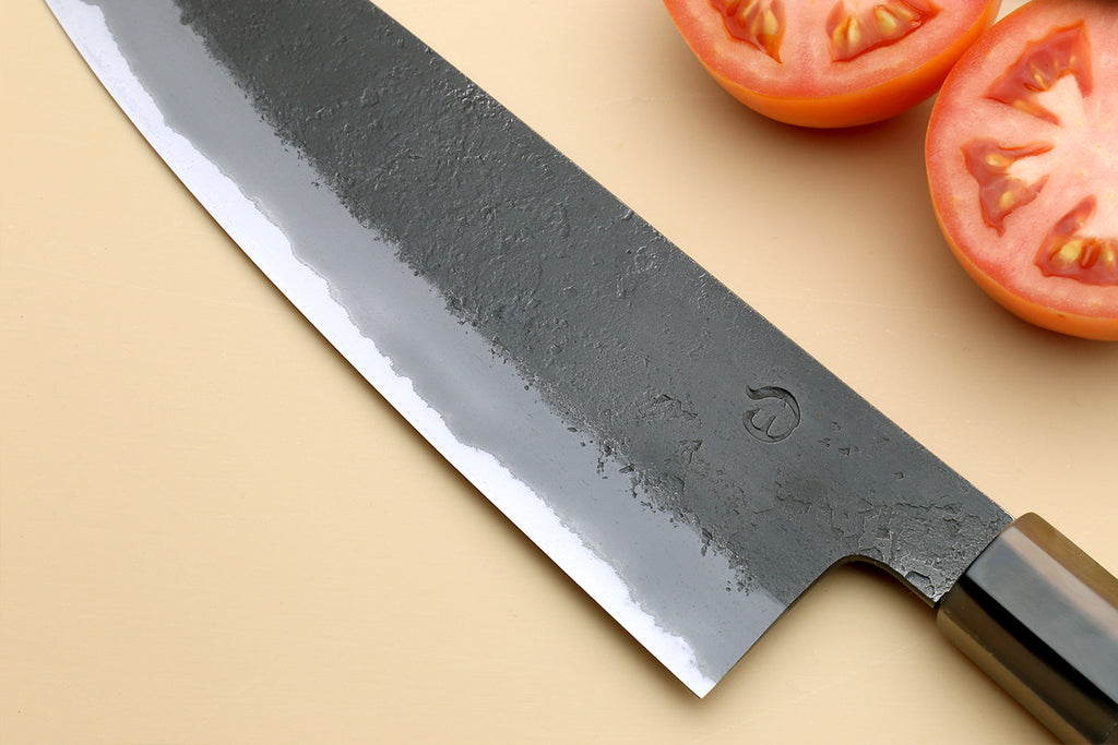Santoku knife blade close-up with hammered texture and dark handle
