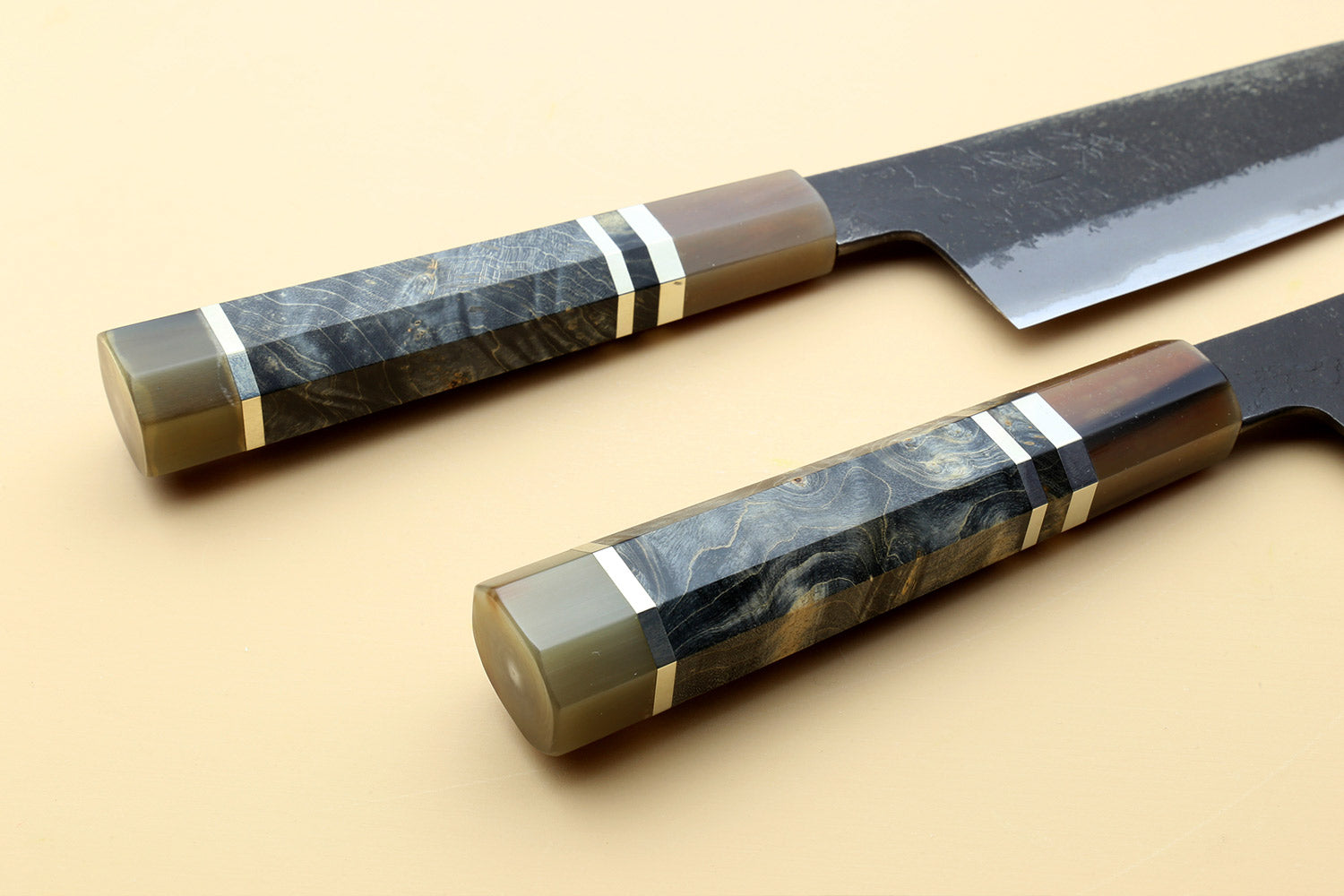 Santoku knives with patterned dark handles and blue-steel blades, side-by-side