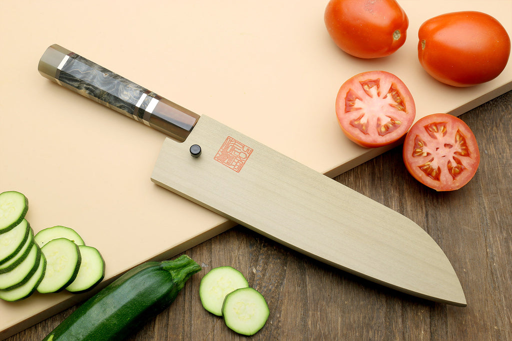 Santoku knife with blue-steel blade and dark handle, with tomato and cucumber slices