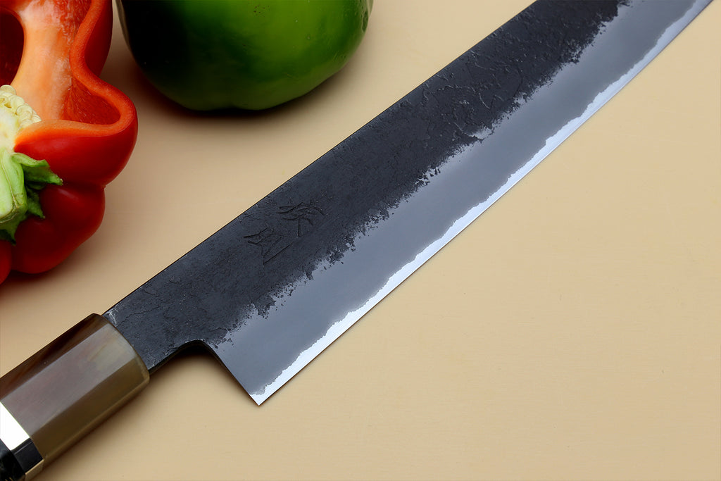 Sujihiki slicer knife close-up, dark blue forged-style blade with brass-toned handle