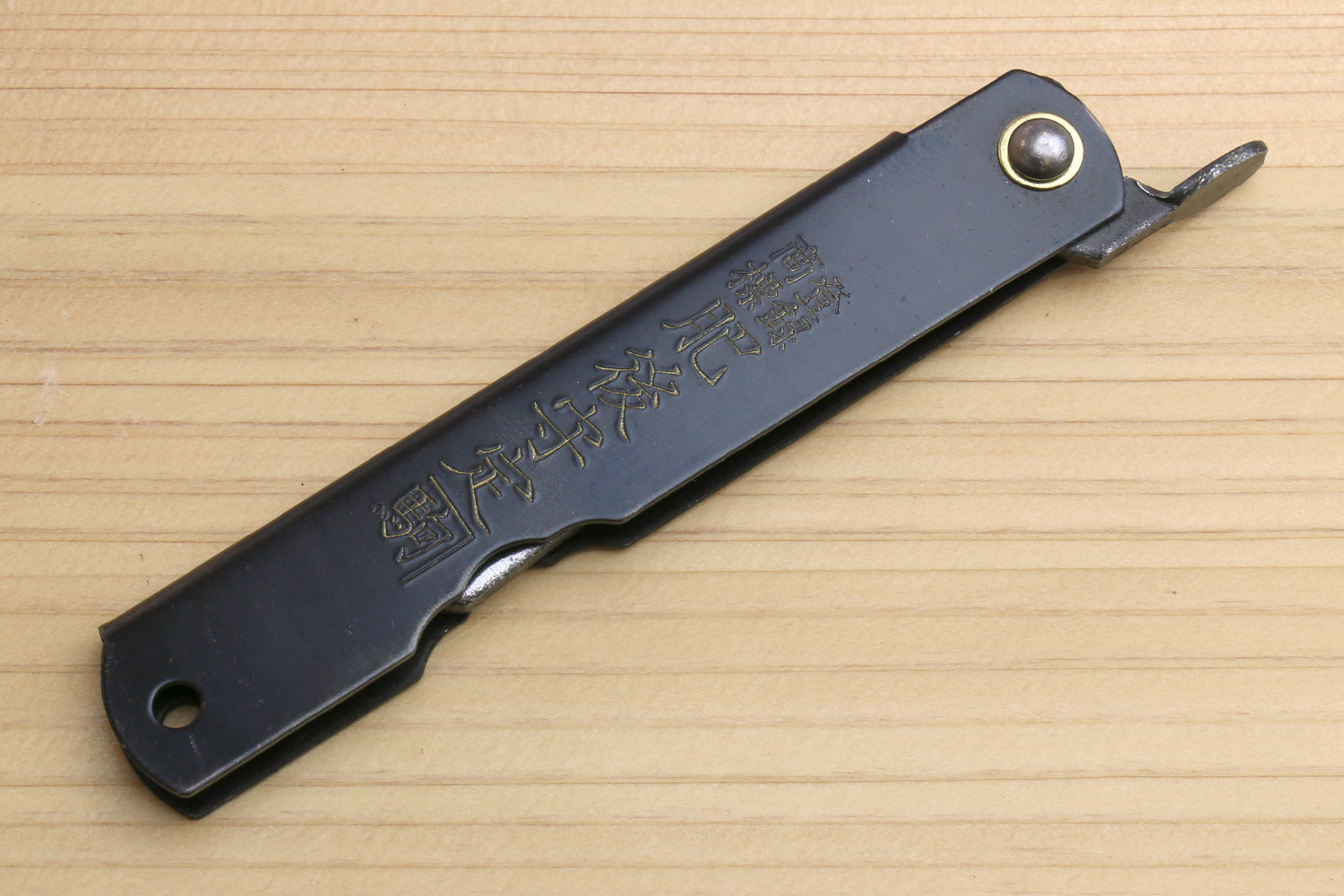 Pocket knife with dark handle and stainless blade edge, round rivet at guard