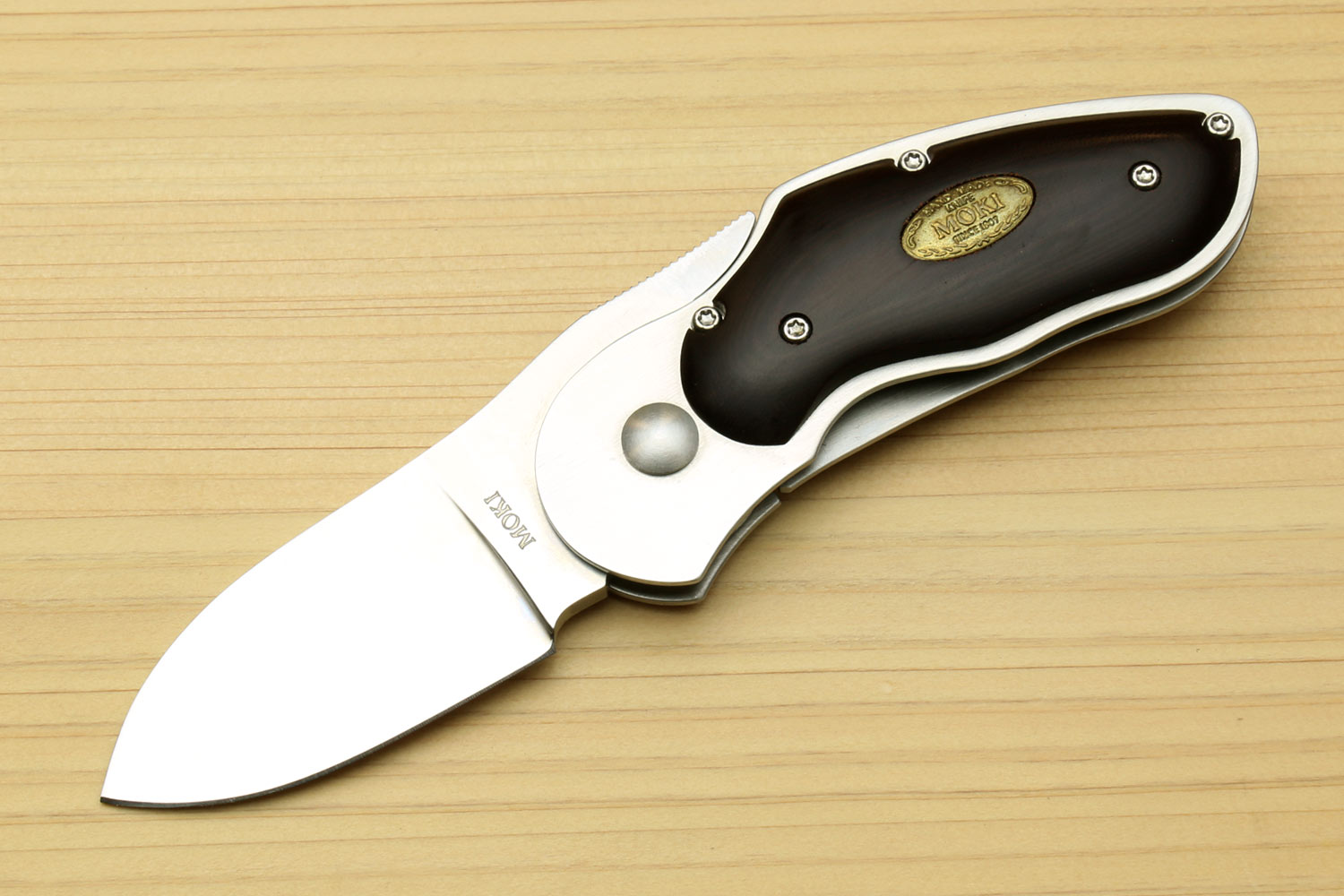 Stainless steel folding pocket knife with black handle and gold shield, polished blade