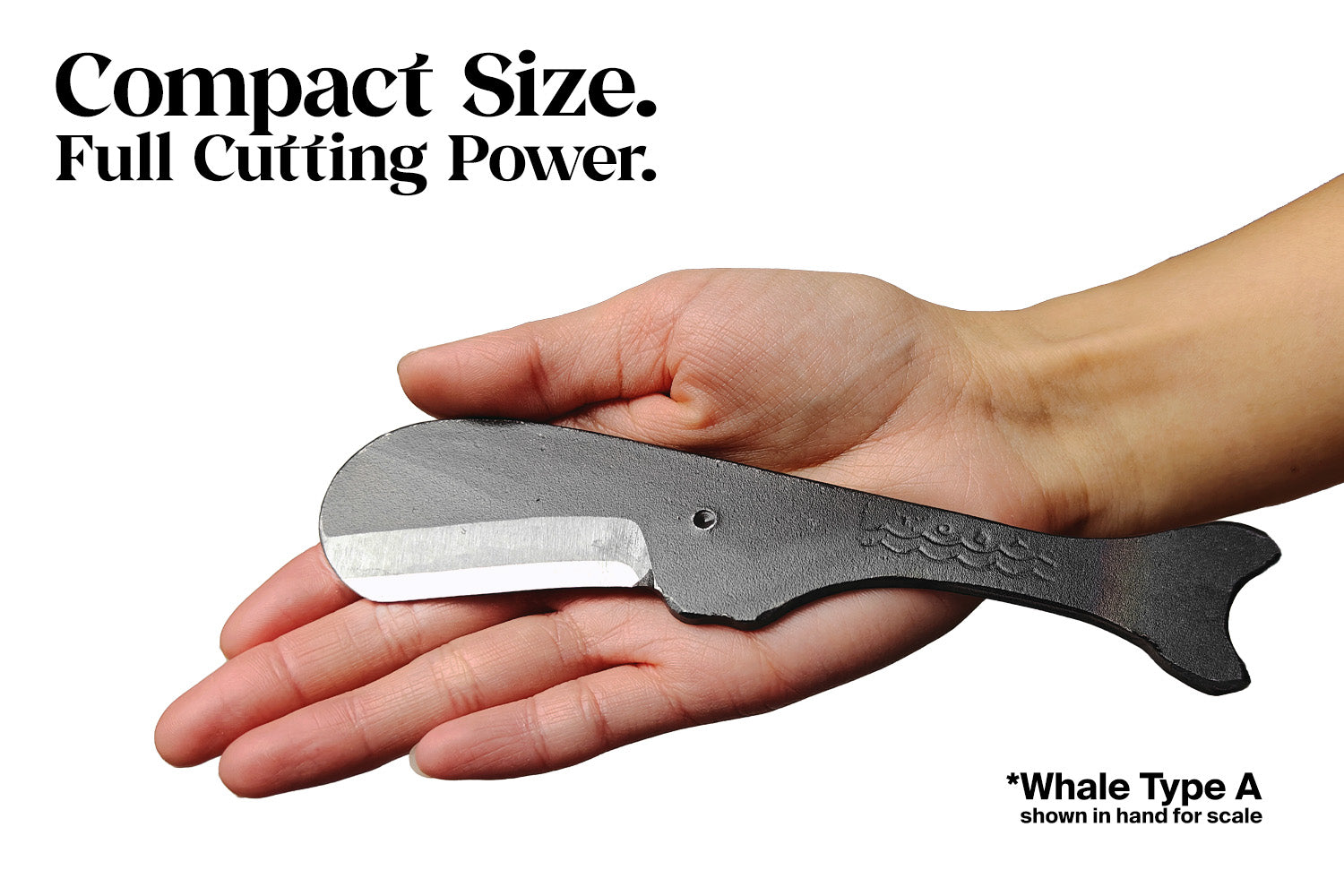 Compact whale utility knife held in hand, dark finish with short curved silver blade