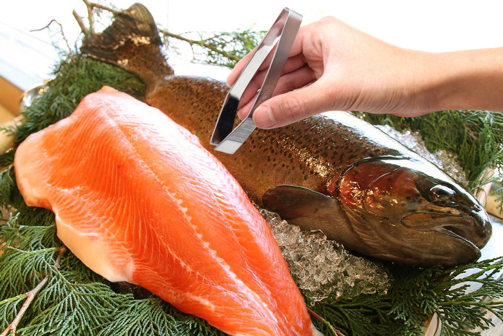 Non-slip fish bone tweezers grasping seafood for garnish, held by a hand.
