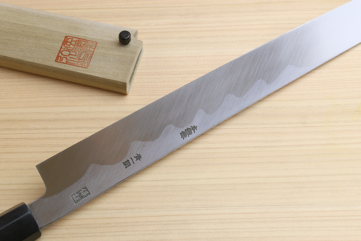 Sakimaru sushi knife blade close-up with etched markings and mirror-polished edge