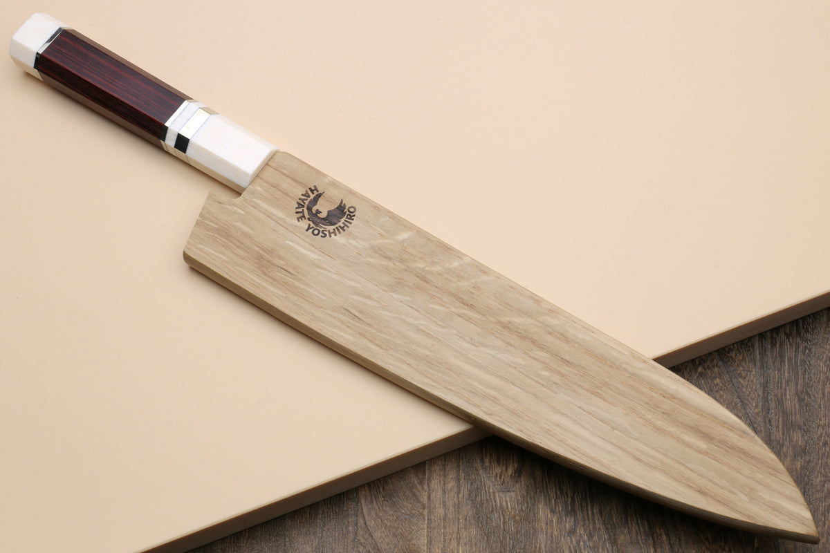 Japanese chef knife resting on a wooden board, rosewood handle and ivory bolster