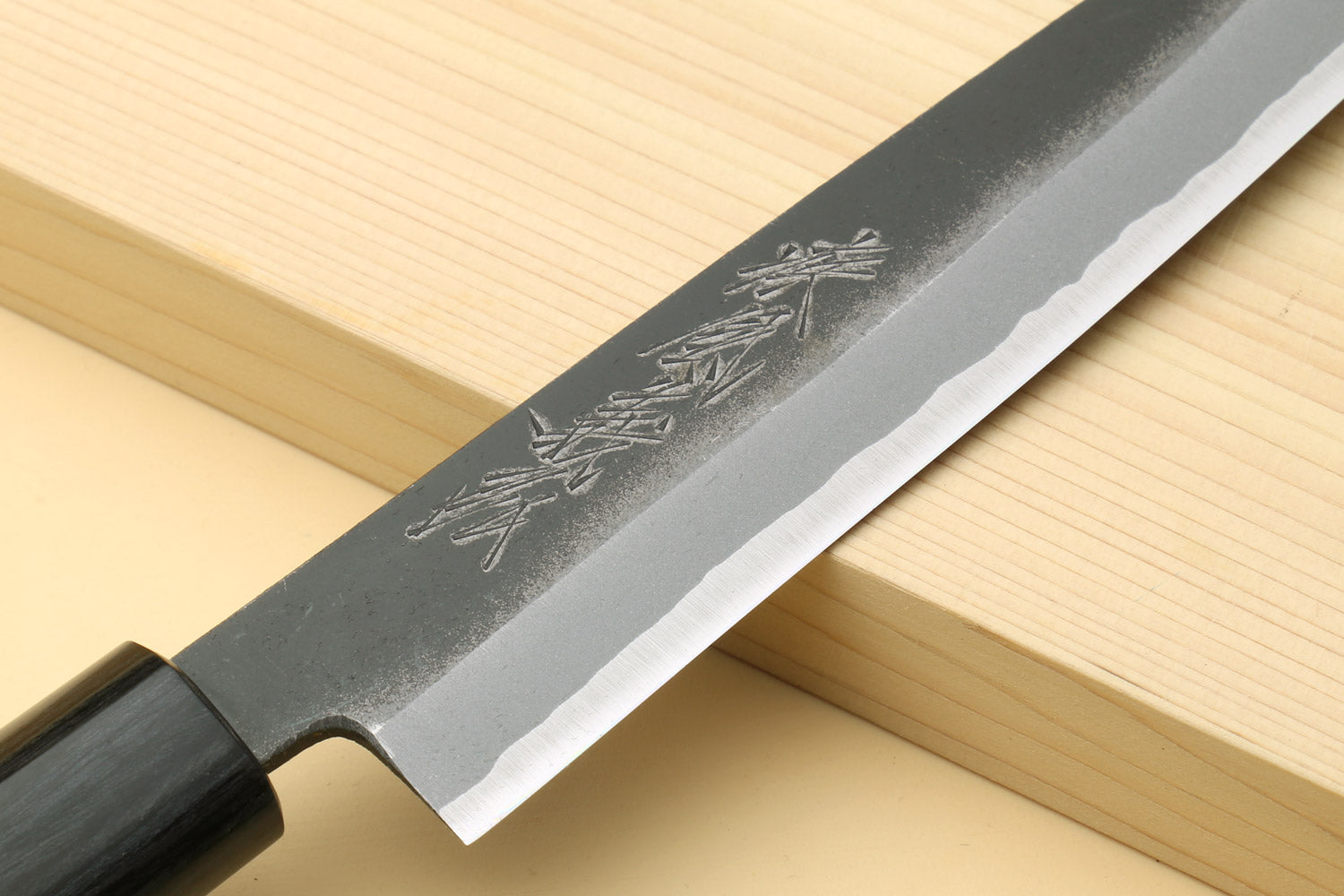Petty knife close-up of blue steel blade with engraved markings and dark handle
