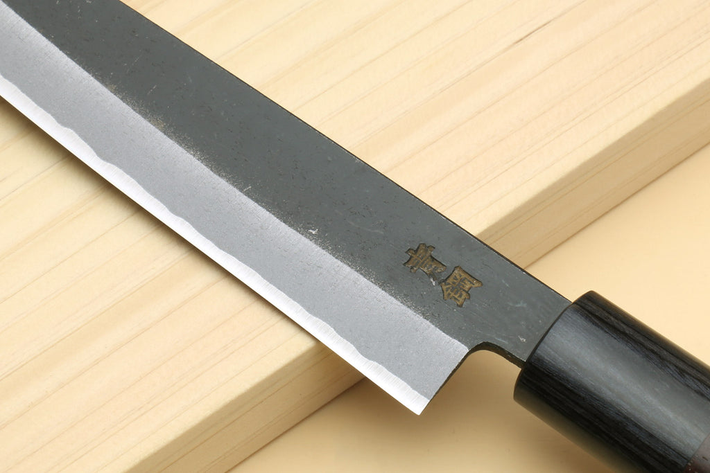 Petty knife blade close-up with engraved logo near bolster and dark wood handle