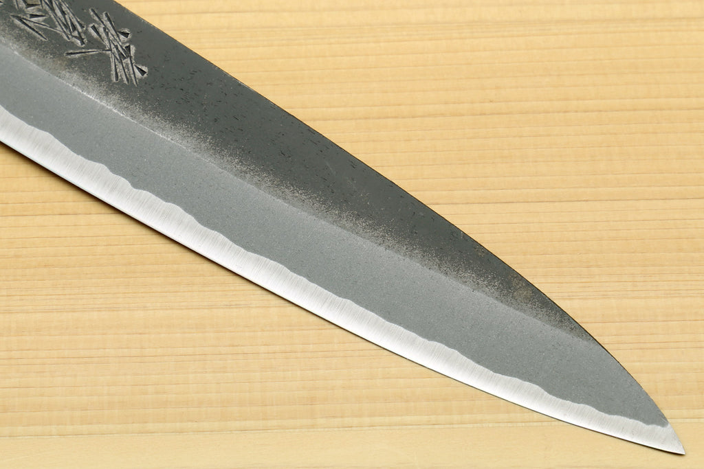 Kurouchi-finish knife blade close-up with textured gray steel and sharp edge