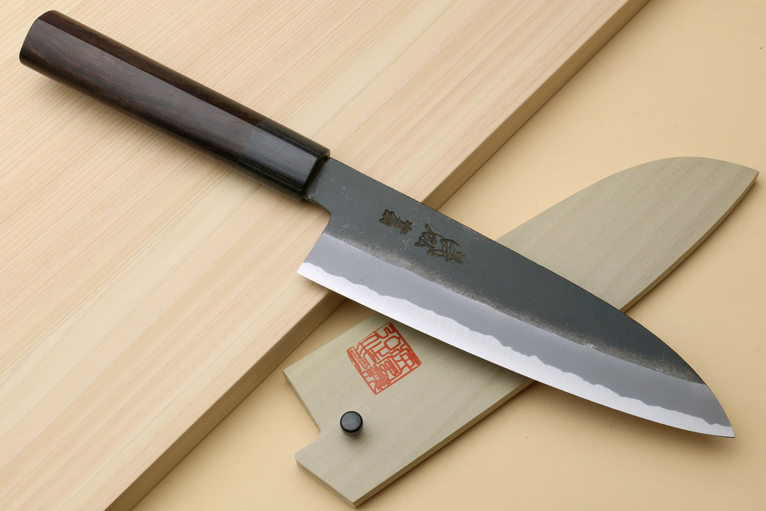 Chef knife with blackened blue steel blade and dark handle, saya cover shown