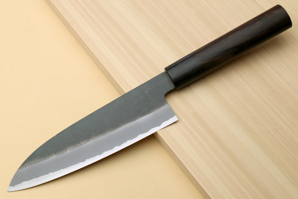 Chef knife with blackened blue steel blade and dark D-shaped handle, angled view