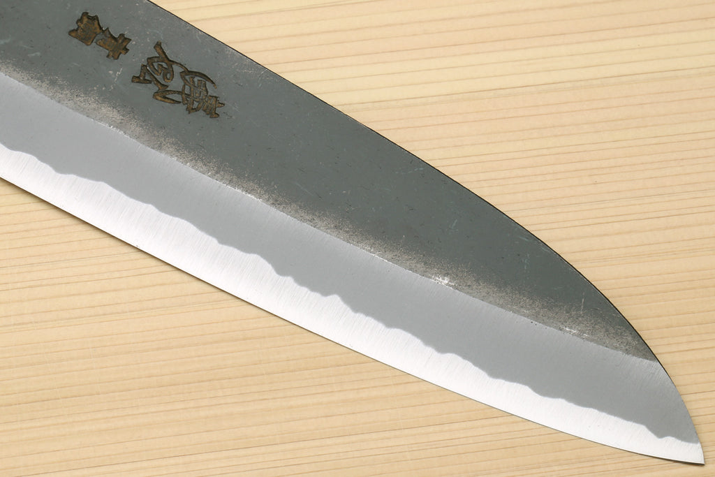 Chef knife with blackened blue steel blade edge and side markings, close-up