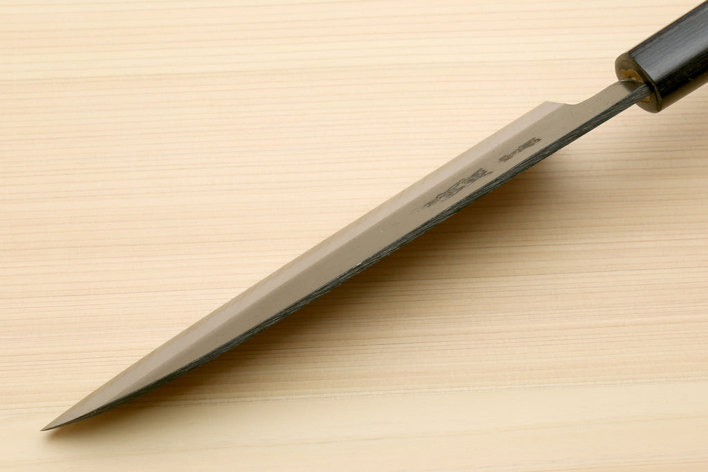 Chef knife with blackened blue steel blade and dark D-shaped handle, tip view