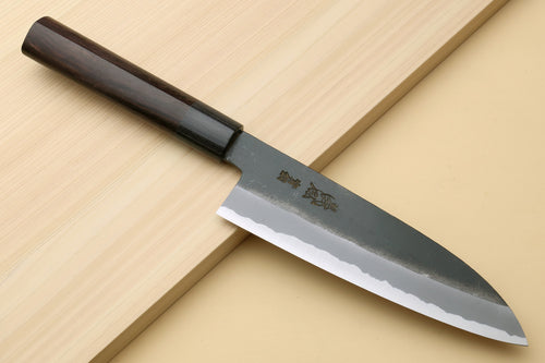 Chef knife with dark D-shaped handle and blackened blue steel blade, side view