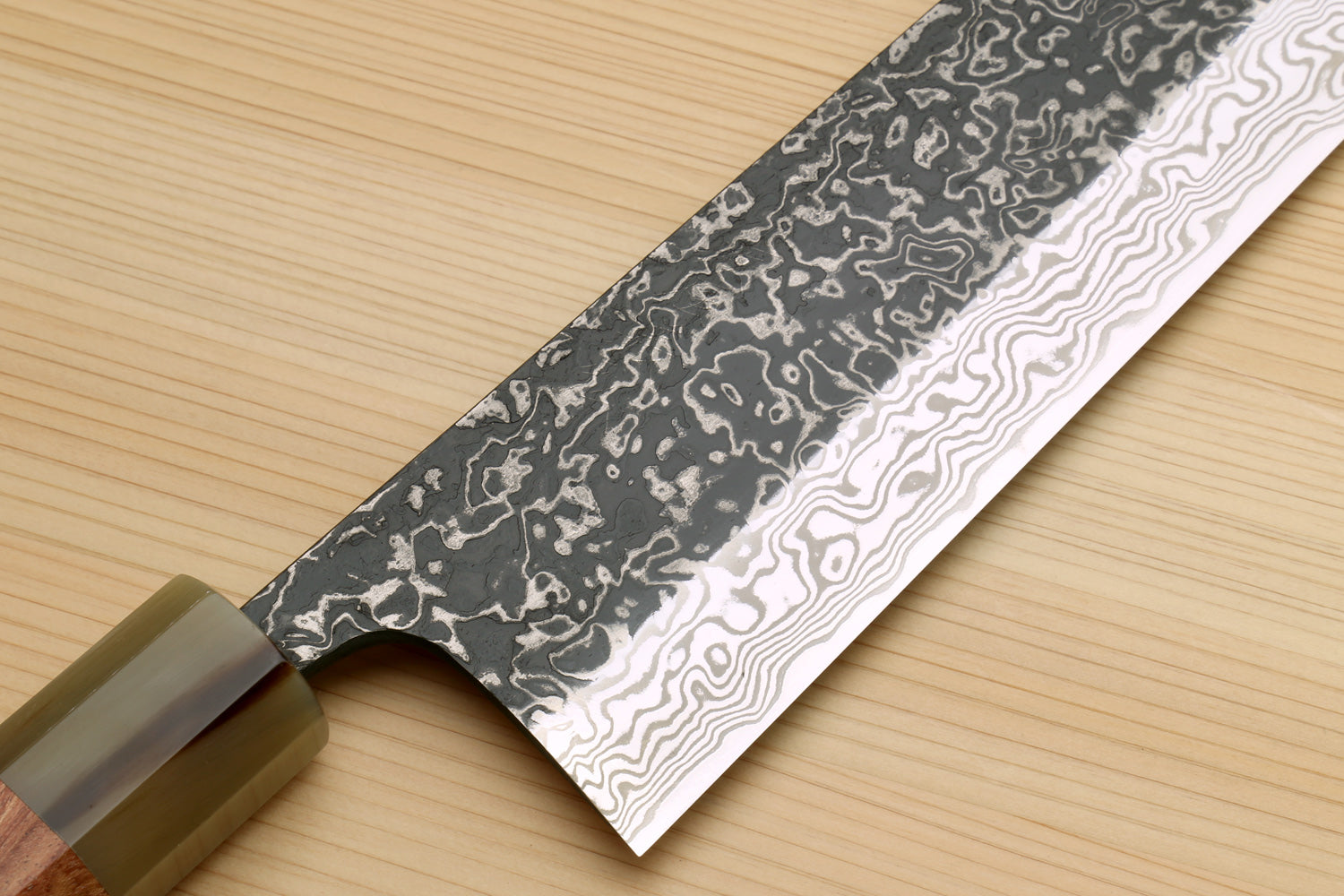 Damascus nakiri blade close-up with ironwood handle; dark forged pattern across edge
