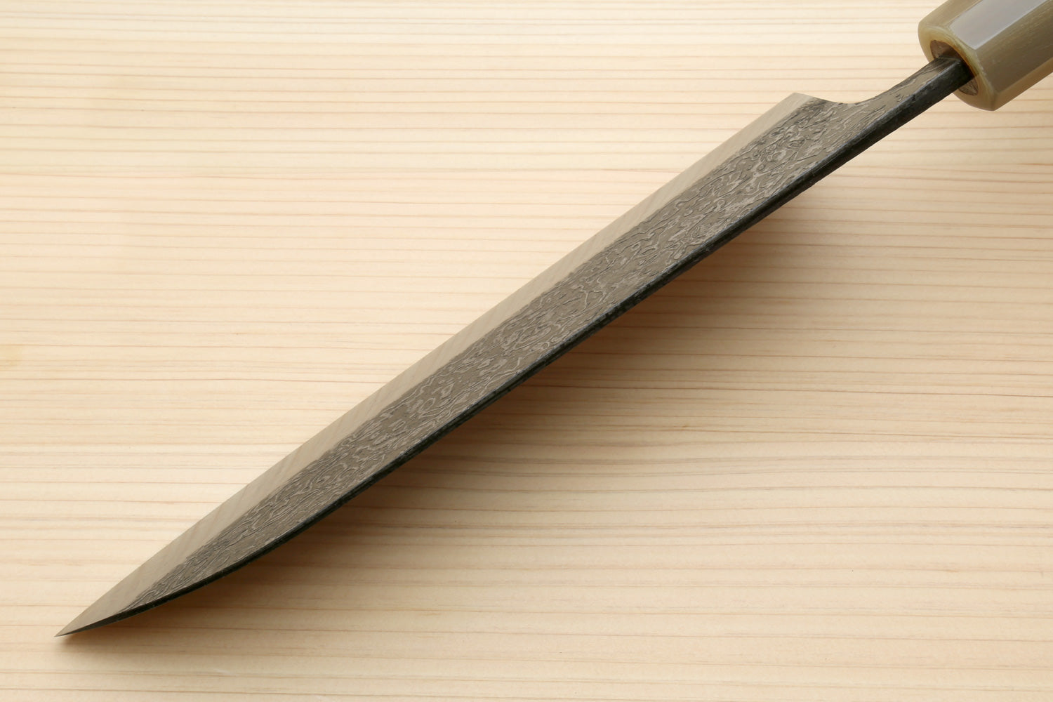 Damascus santoku blade in profile with dark spine and sharpened edge