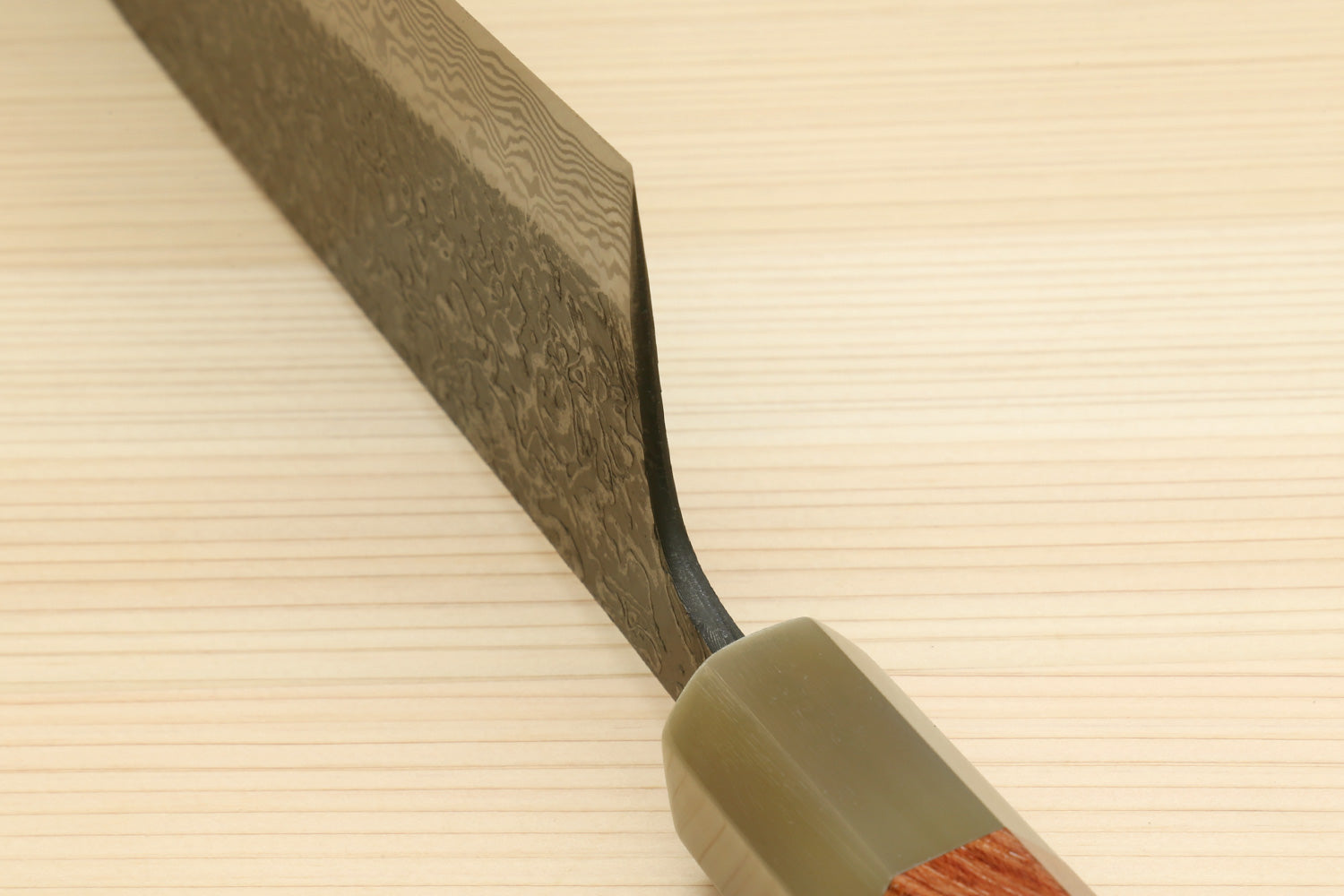 Santoku knife with ironwood handle and dark Damascus blade near bolster