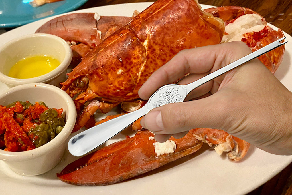 Stainless crab & lobster spoon held in hand, 7.75 in, oval bowl with seafood engraving