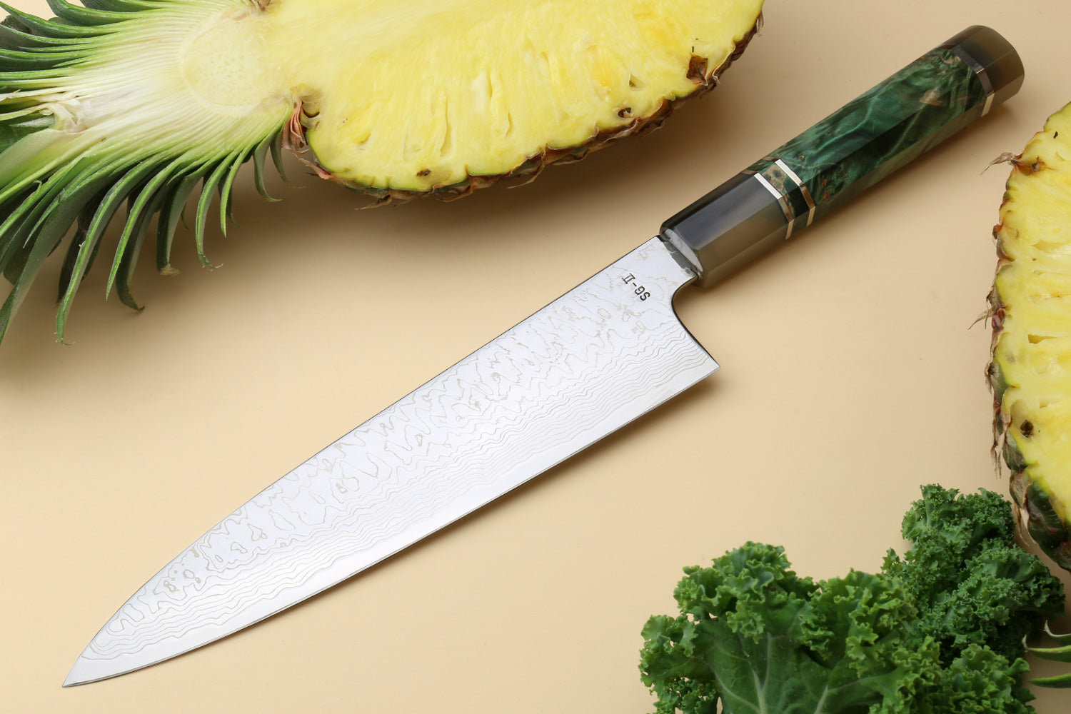 Damascus gyuto chef knife with patterned blade and dark green handle, triple ring accents