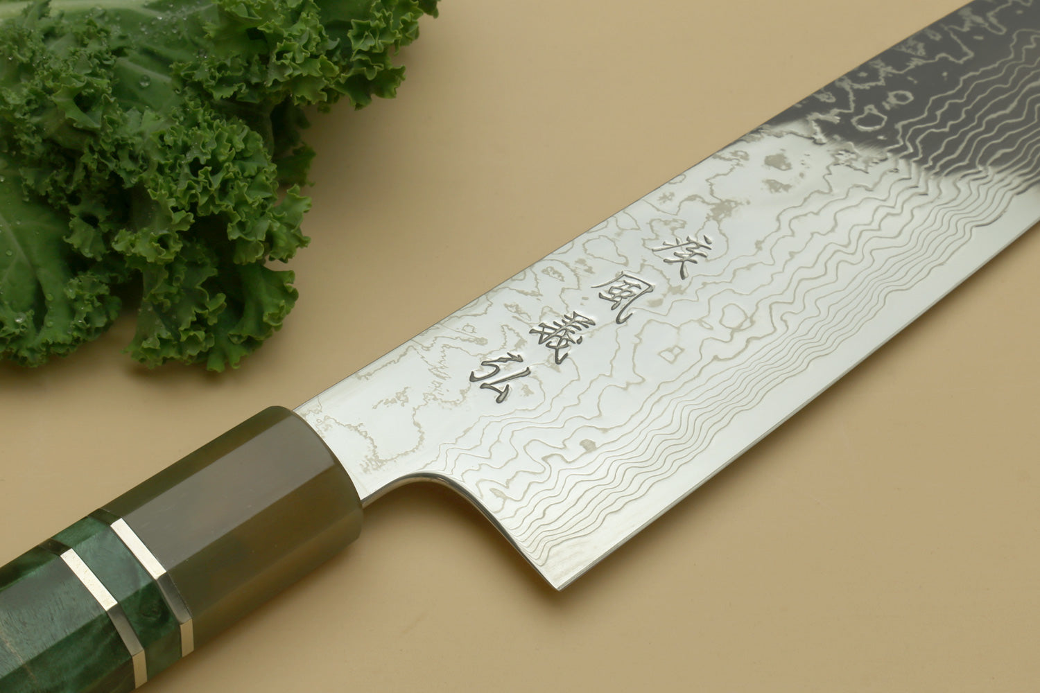 Damascus gyuto knife with wavy blade pattern and dark green handle with brass bolster