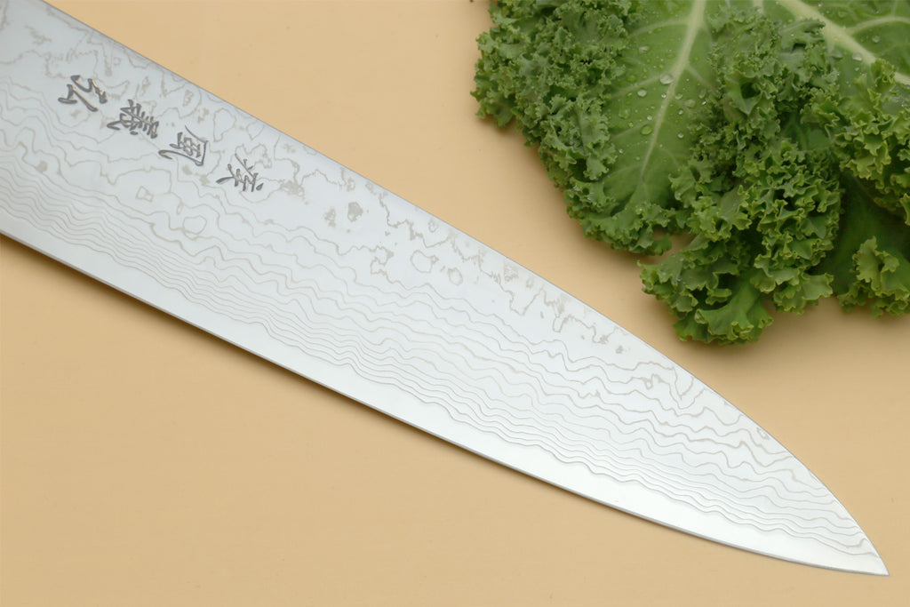 Damascus gyuto chef knife blade close-up with wavy pattern and engraved markings