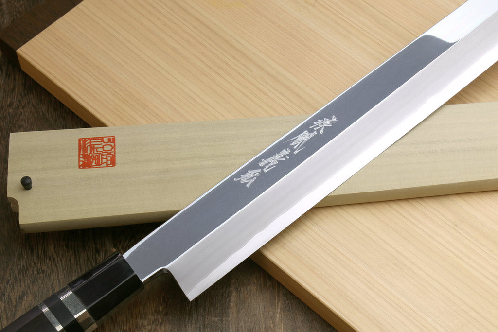 Tuna knife close-up: mirror-polished steel blade with etched marks and black handle