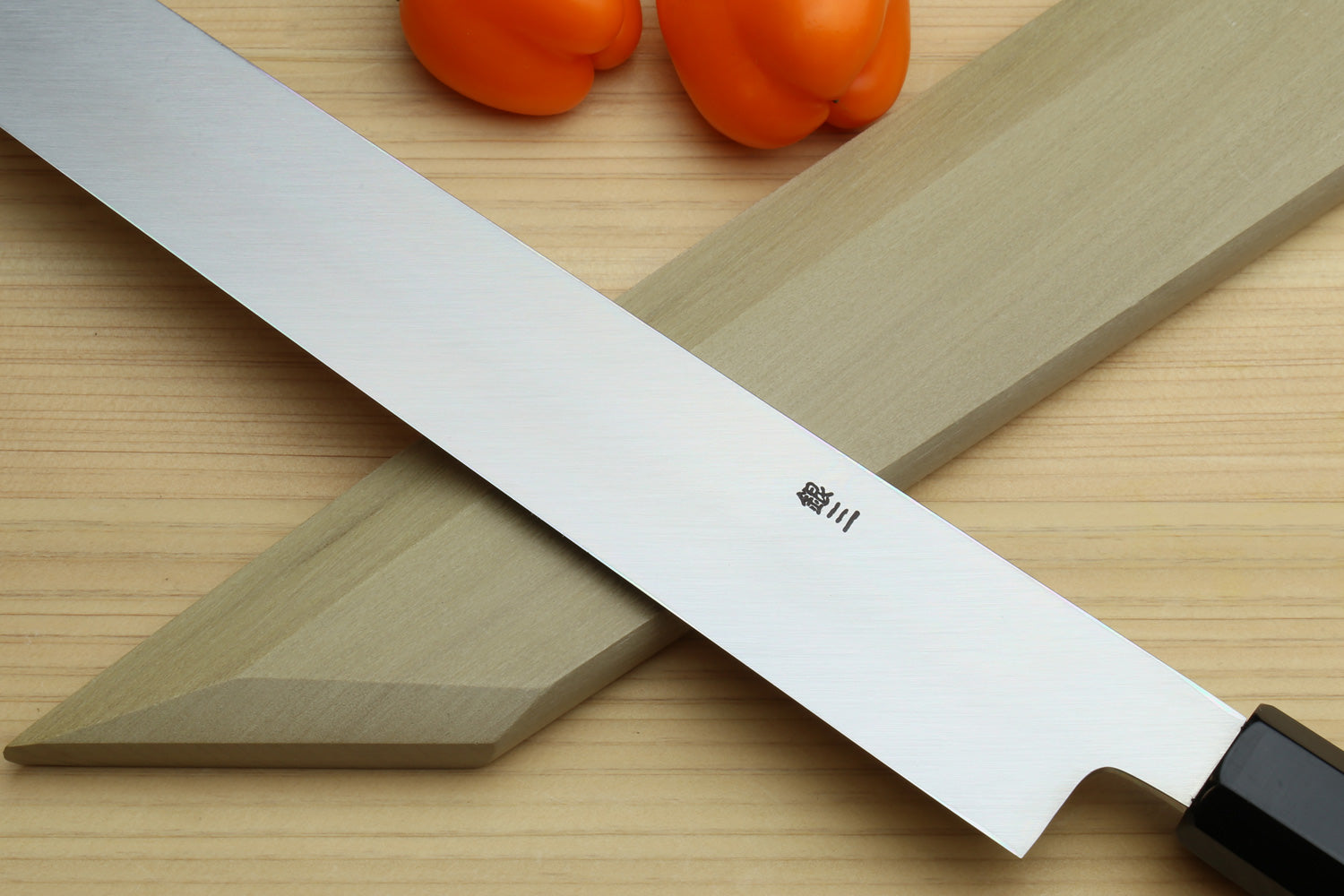 Yanagi kiritsuke knife close-up: mirror-polished blade with dark handle