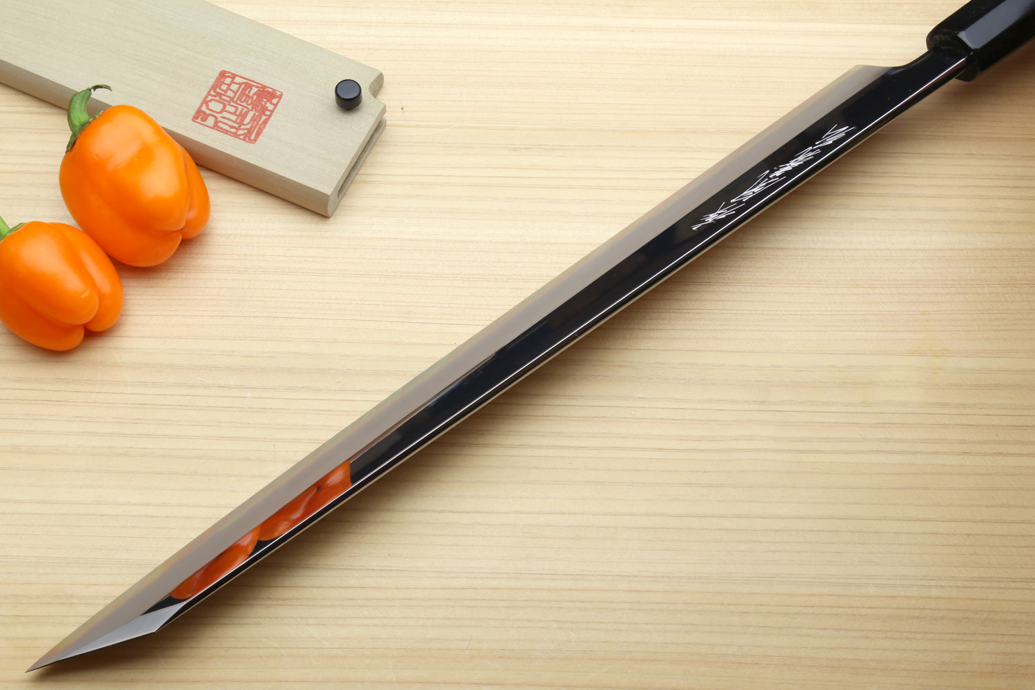 Japanese Yanagi kiritsuke knife with mirror-polished edge and dark handle