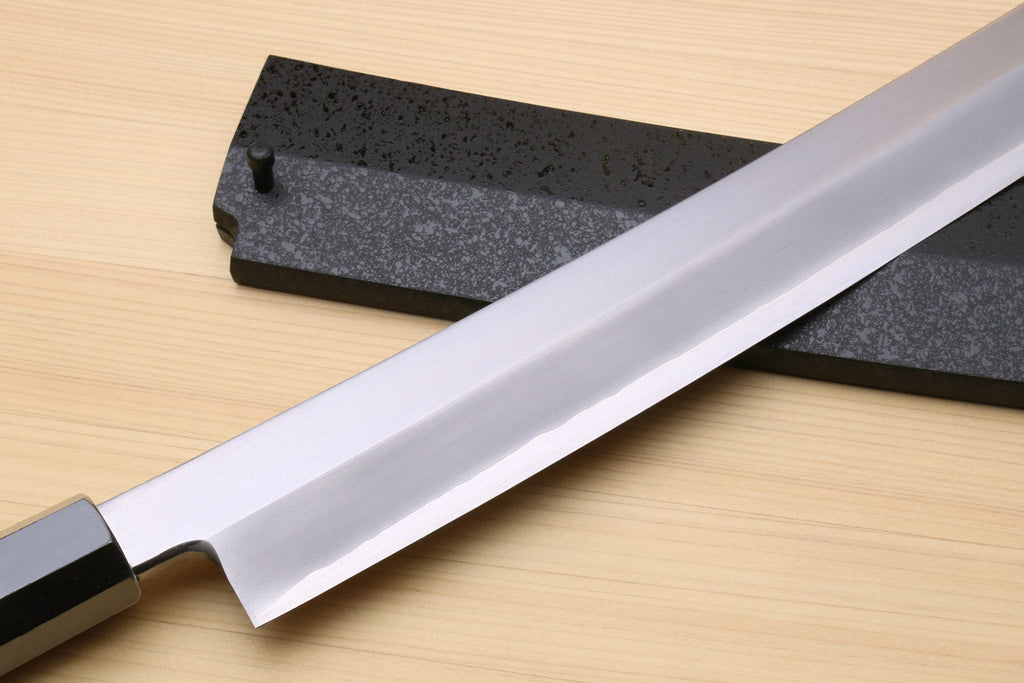 Tuna knife blade close-up with silver steel finish and dark textured guard