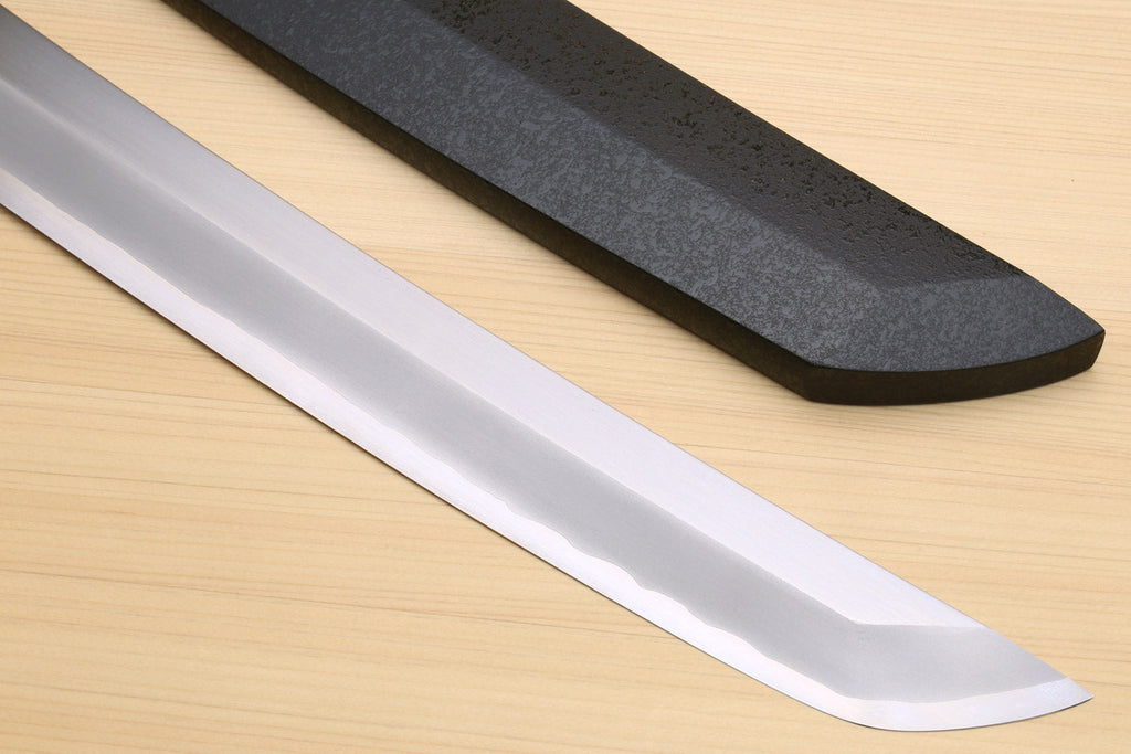 Tuna knife blade and black saya, long silver edge on a light wood surface