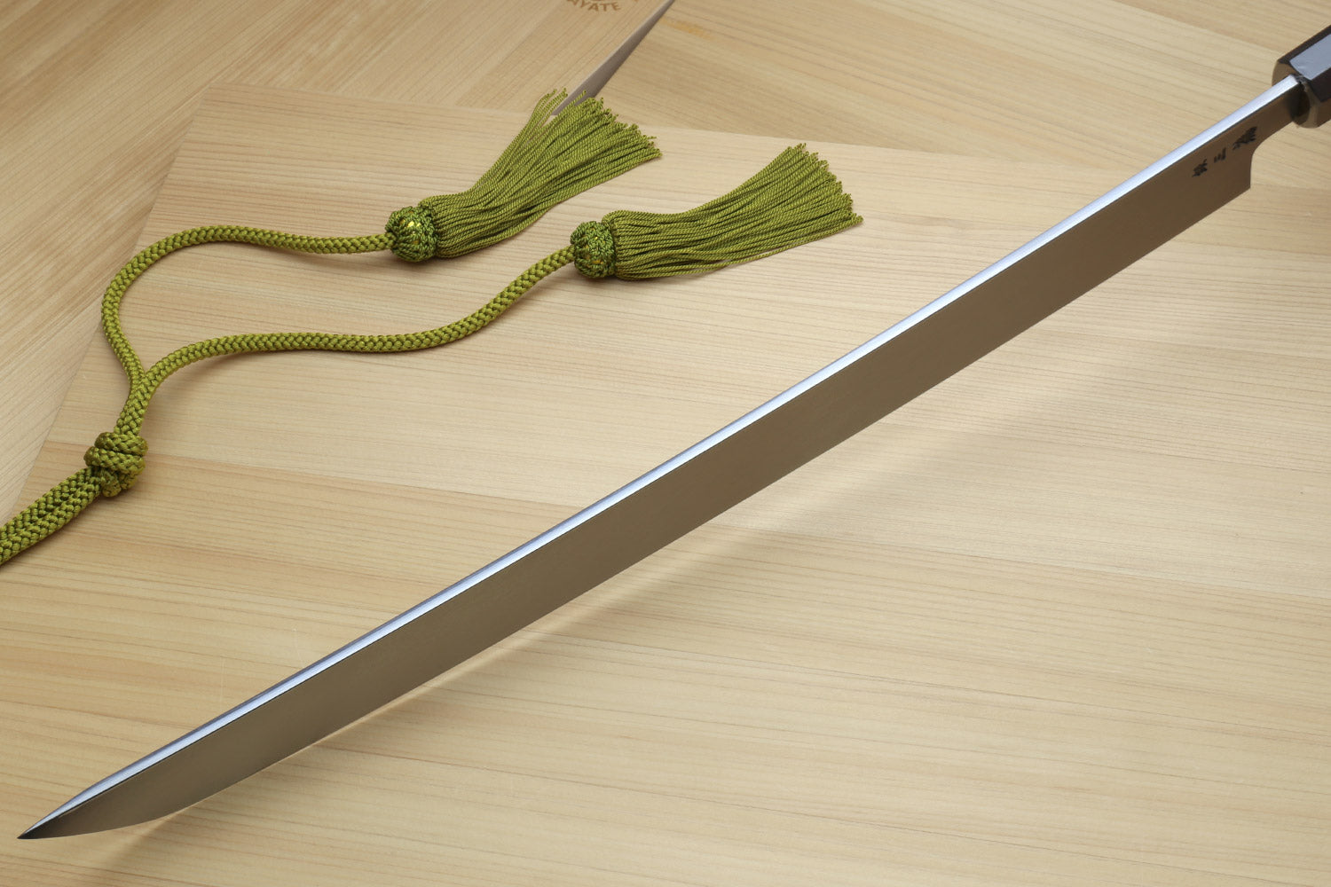 Tuna knife with long silver blade and dark handle, plus green tassel cord