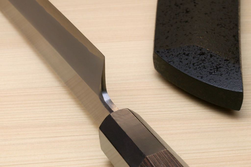 Tuna knife bolster and heel close-up with dark handle on a wood board