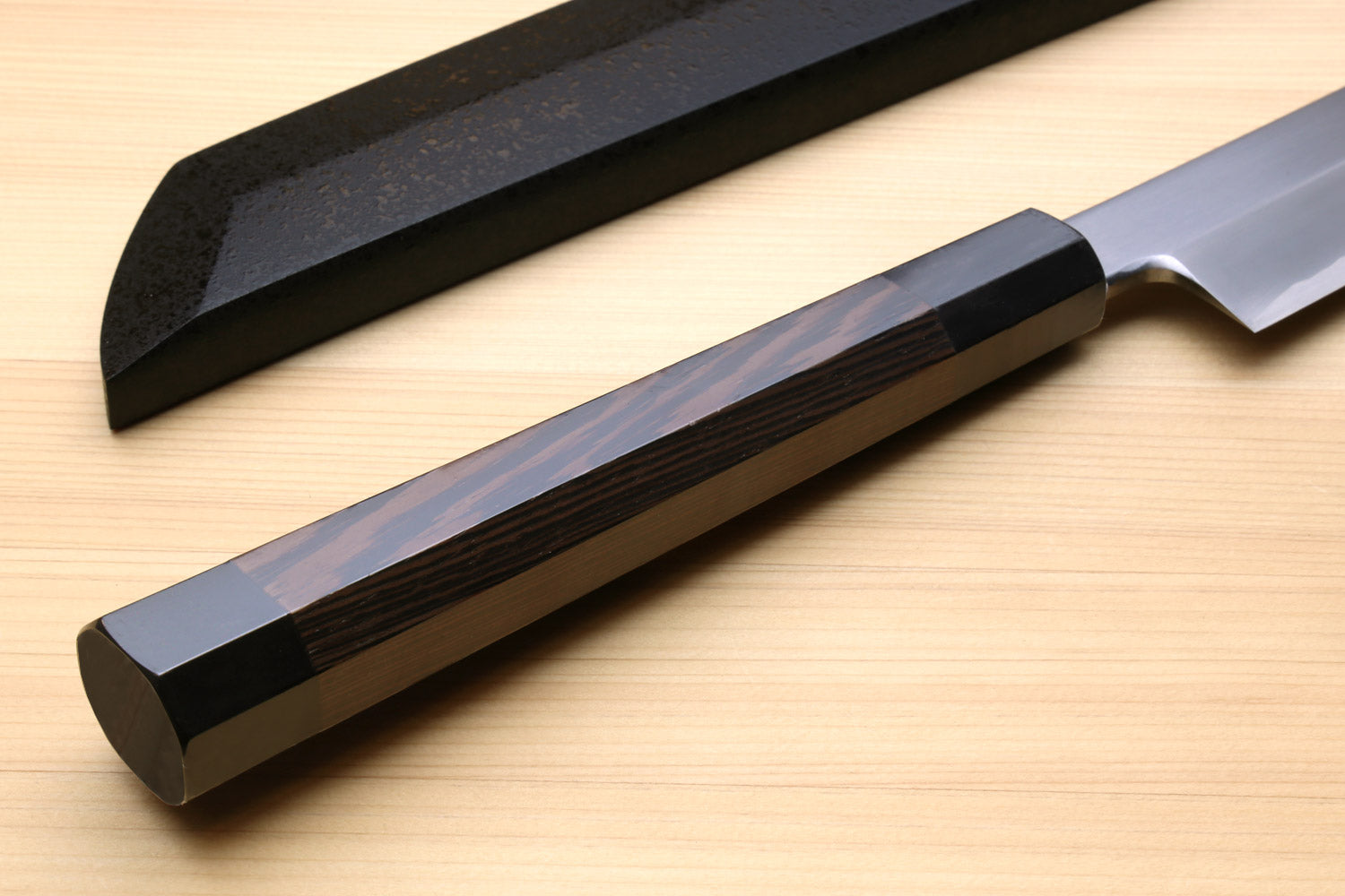 Tuna knife handle close-up with dark wood grip and silver blade above saya