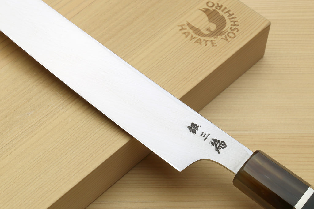 Yanagiba knife blade with etched characters and curved profile; ebony handle with metal collar
