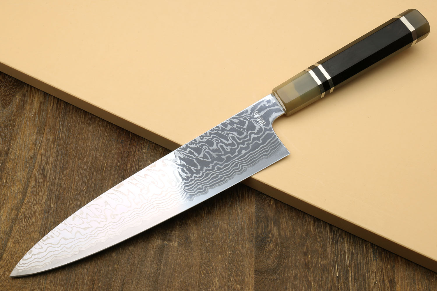 Damascus gyuto chef knife with octagonal ebony handle and triple-ring bolster, angled