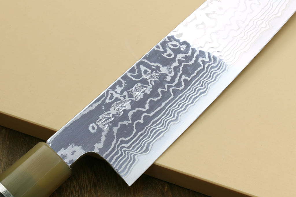 Damascus gyuto chef knife blade close-up with wavy pattern and dark handle section