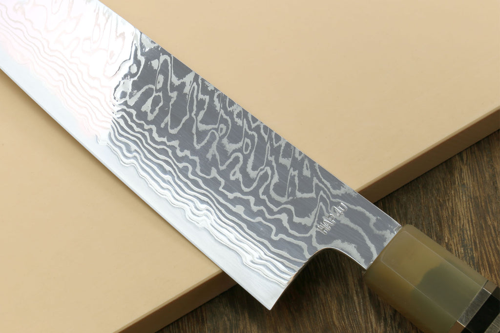 Damascus gyuto chef knife blade close-up with wavy Damascus pattern and bolster