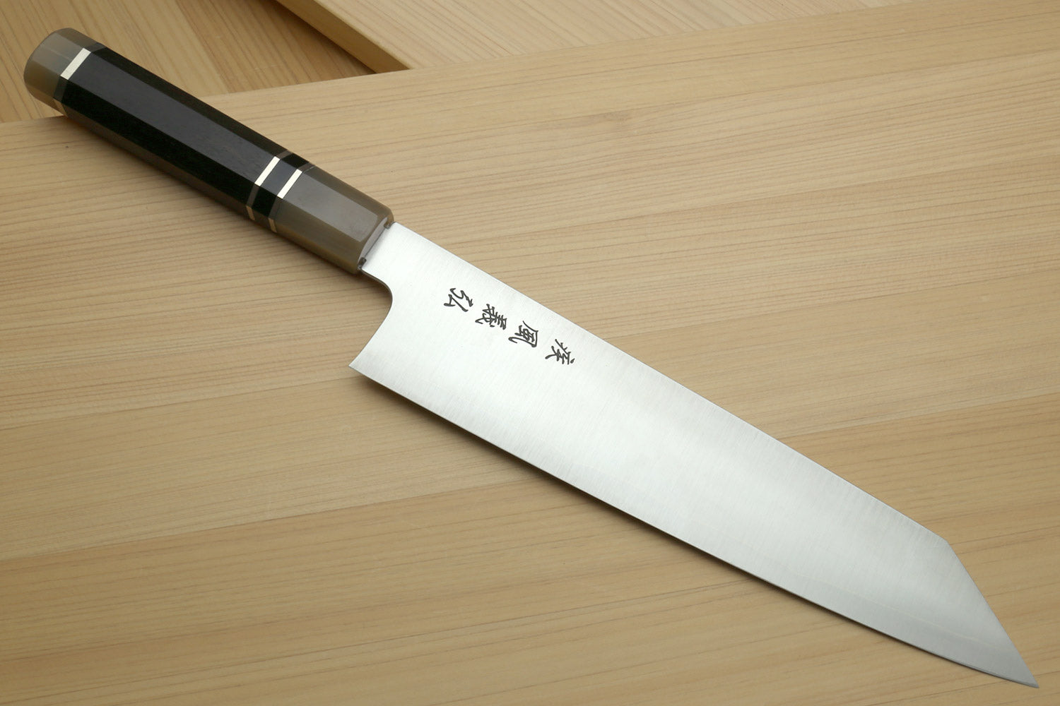 Kiritsuke chef knife with stainless blade and ebony handle, angled view