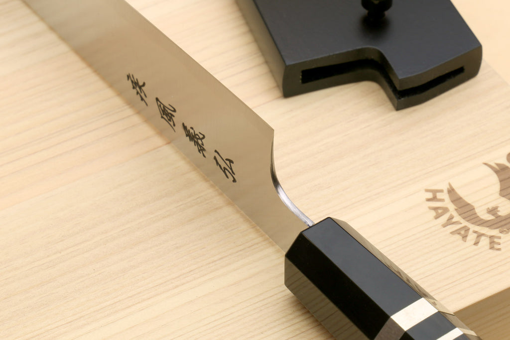 Sujihiki slicer knife with curved blade edge and black blade guard on wood