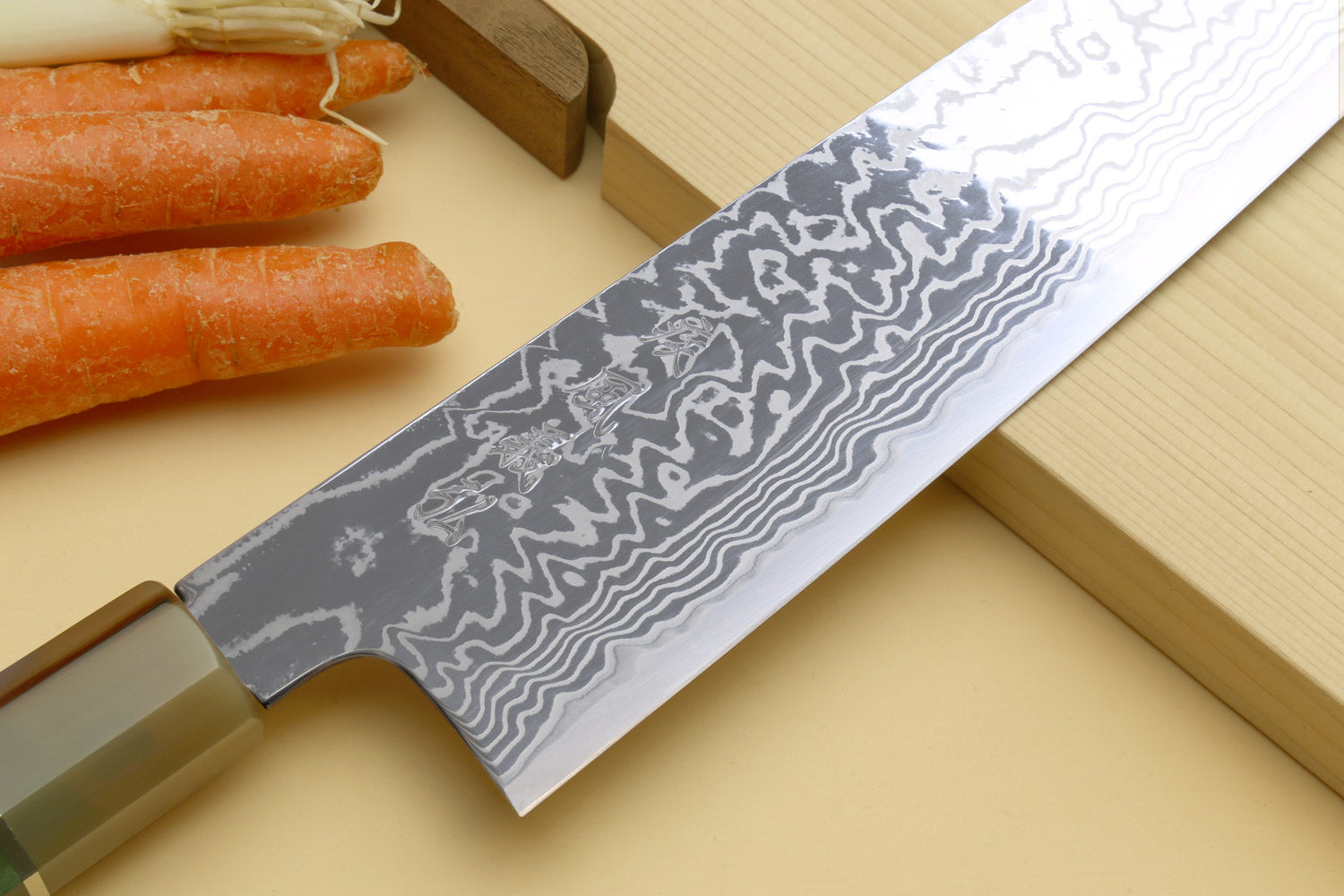 Chef's gyuto knife showing Damascus blade pattern and brass bolster
