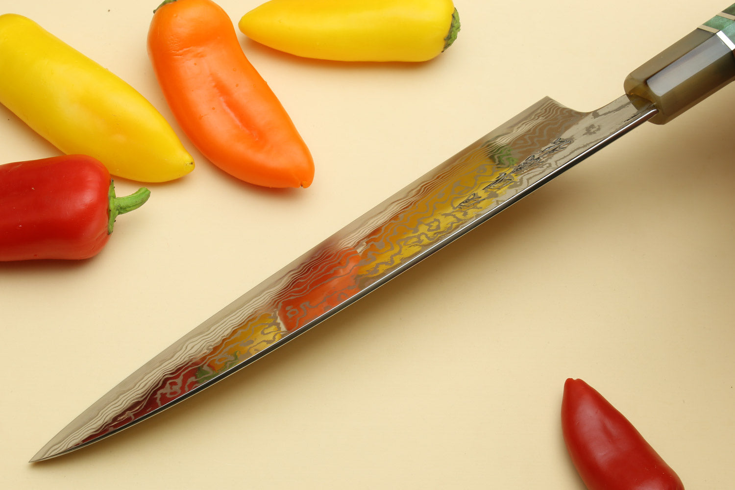 Gyuto chef knife with mottled Damascus blade and brass bolster at spine