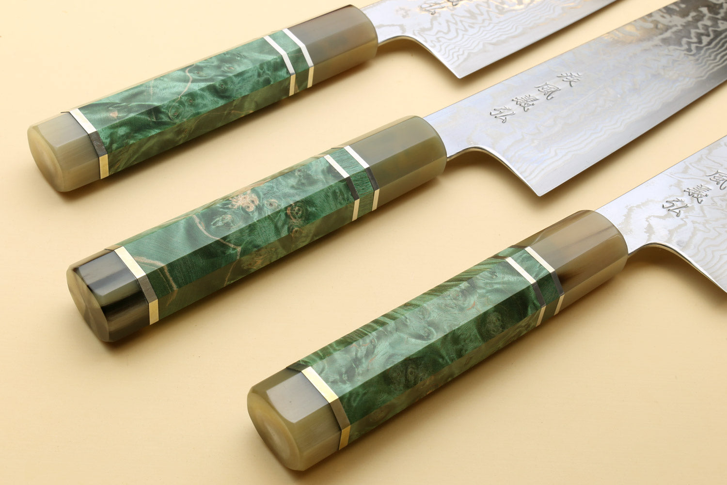 Set of gyuto chef knives with green burl handles and Damascus-pattern blades